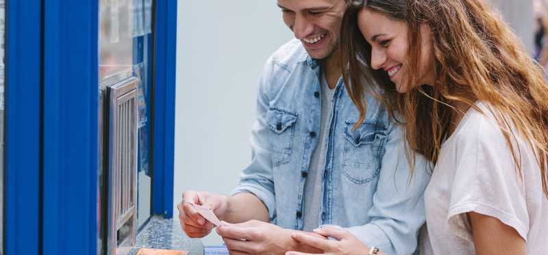 Two people smile while buying lottery tickets.
