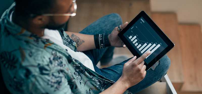Person sitting on staircase is looking at stock chart on a tablet.