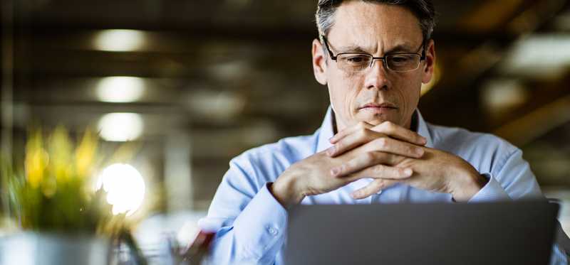Person looking pensively at computer screen.