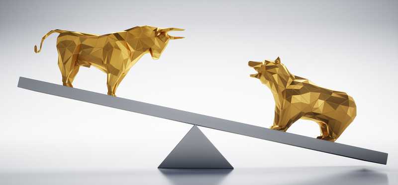 Golden bull and bear facing off while balancing on seesaw.
