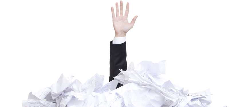 Person's arm sticking up out of a pile of papers.