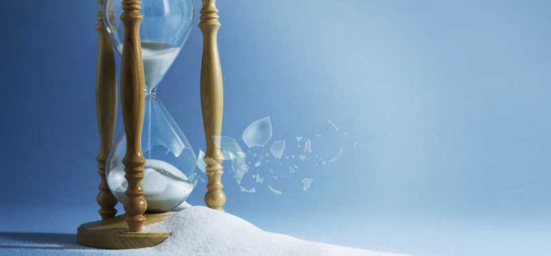 Sand flowing through hourglass against blue background