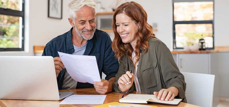 Two people smiling and looking at document.