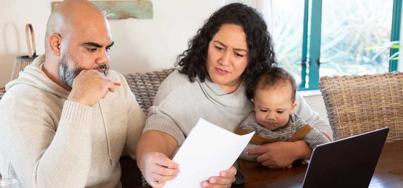 Adults sitting with baby while reviewing paperwork.