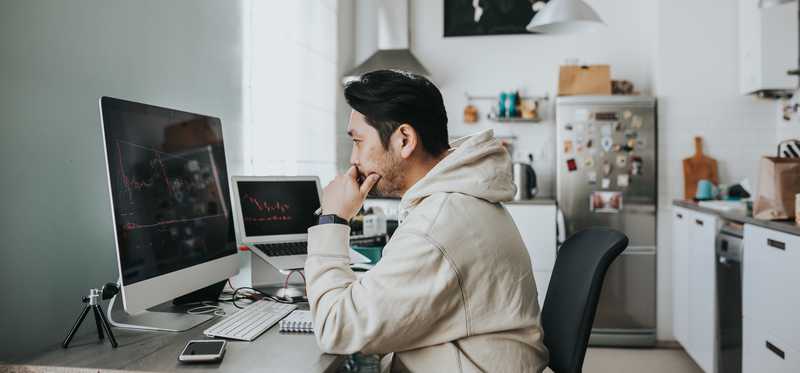 Man looking intently at computer screens in kitchen