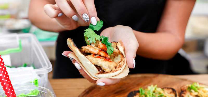 Person preparing tacos on pita bread.