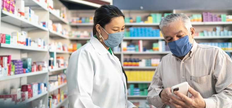 Pharmacist and patient looking at phone screen