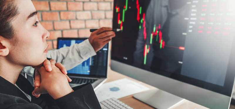 Person tracking stock movements on large monitor.