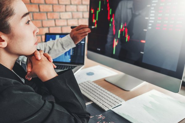 Person tracking stock movements on large monitor.