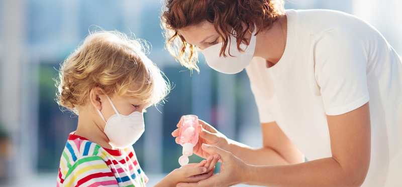 Mother giving her small child hand sanitizer