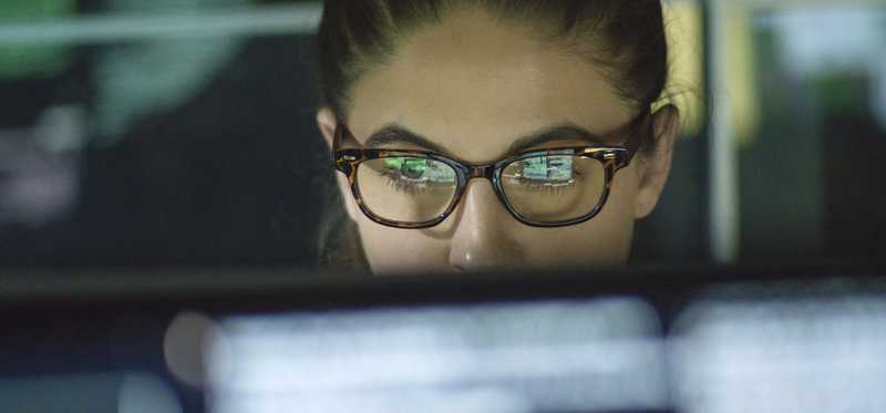 Woman with glasses showing reflection of her computer screen