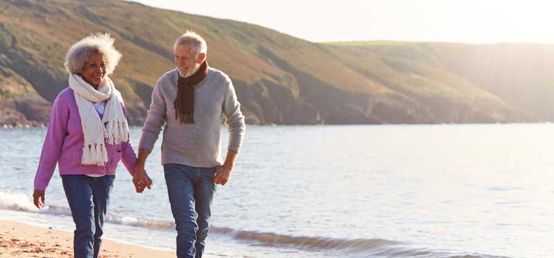 Older couple walking on the beach and holding hands