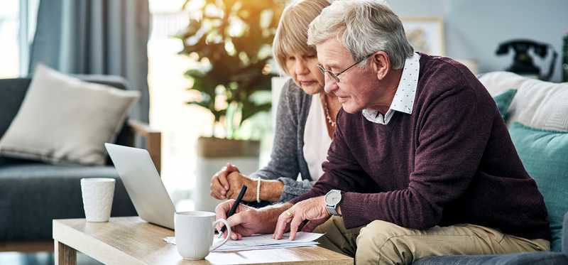Senior couple looking at laptop and documents.