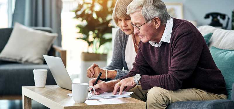 Senior couple looking at laptop and documents