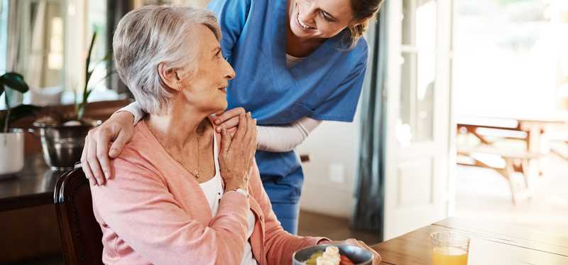 Senior woman in a nursing home talking to a nurse.