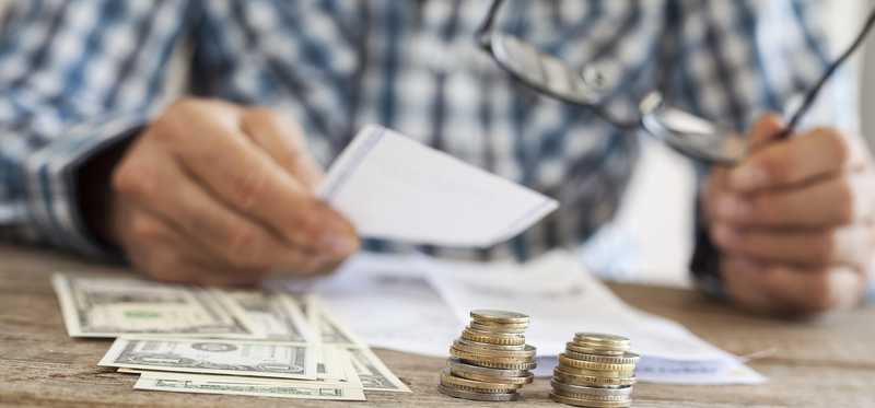 Man looking at documents with coins and dollar bills in front of him