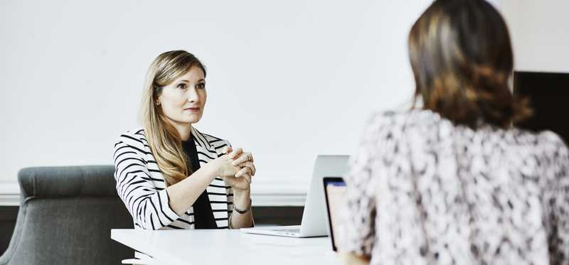 Businesspeople with laptops and tablet meeting at table.