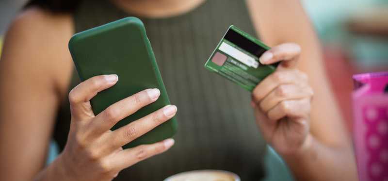 Person buying coffee using mobile app and credit card.