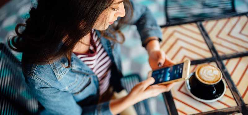 Person sitting in coffee shop and looking at phone.