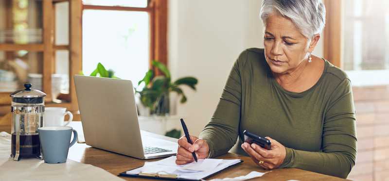 Person taking notes while looking at phone.