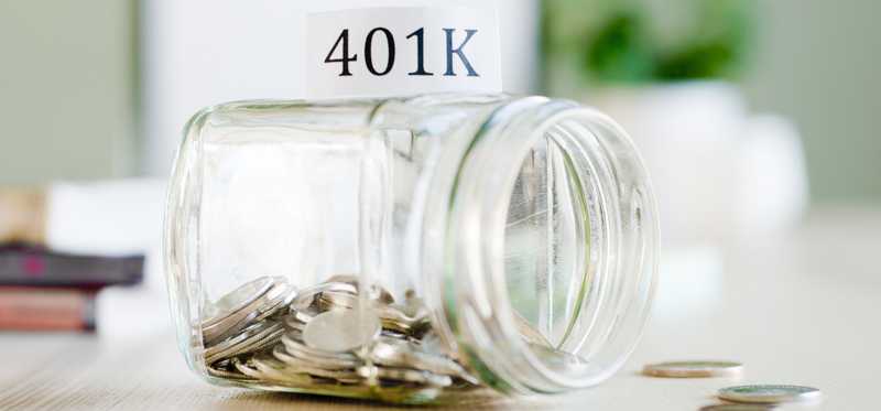 A glass jar with coins and sign reading 401k in the background.