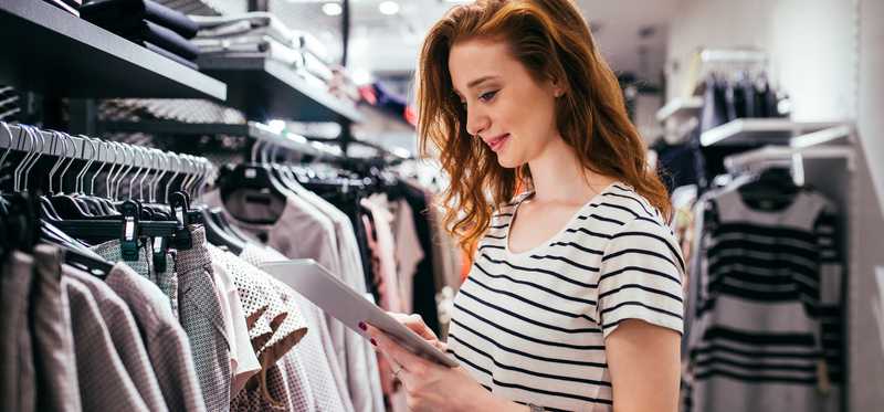 A person in a clothing store using a tablet.