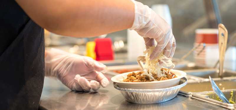 Worker making a burrito bowl at Chipotle