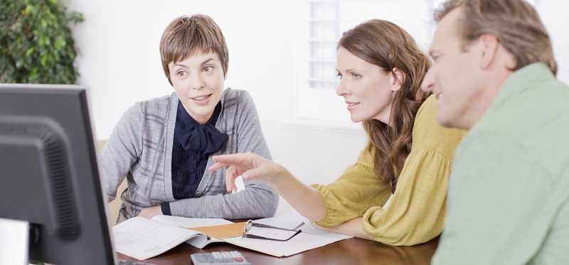 Financial advisor meeting with clients in office setting.