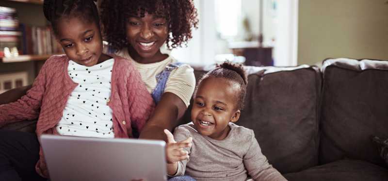 Three people happily looking at laptop.