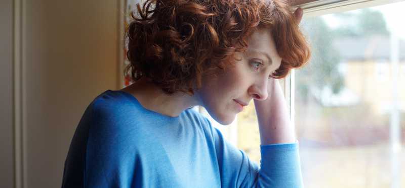 Person looking pensively out a window.
