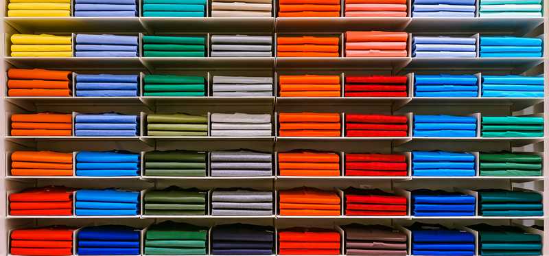 Shelves of folded shirts sorted by color