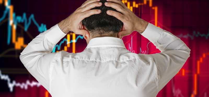 Person grabs head in frustration while looking at wall of charts.