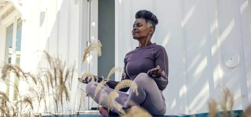 Person sitting on back deck and doing yoga pose.