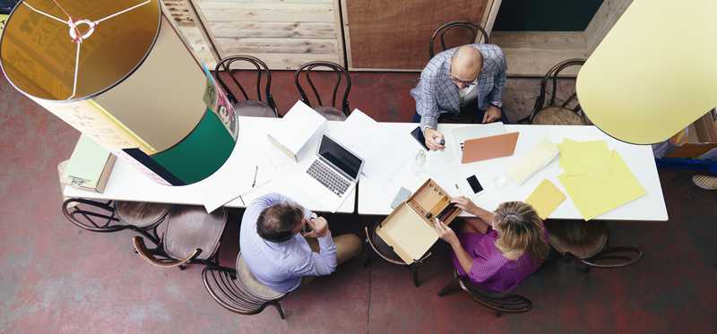 Employees sitting in office working at long table as seen from overhead