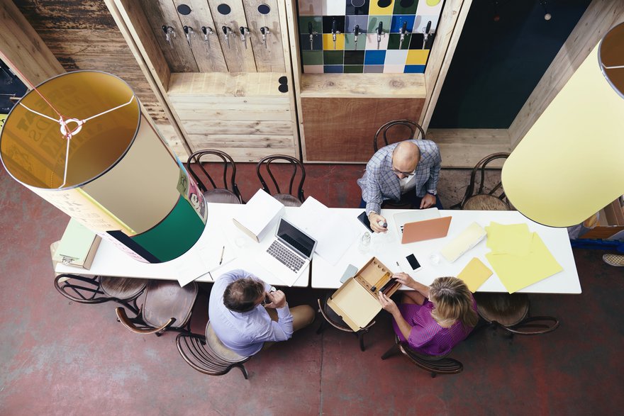 Employees sitting in office working at long table as seen from overhead