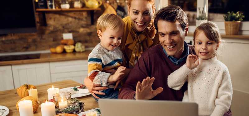Family of four in front of laptop video chatting with loved ones
