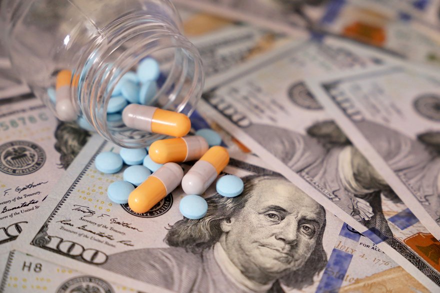 Capsule pills spill onto scattered hundred dollar bills
