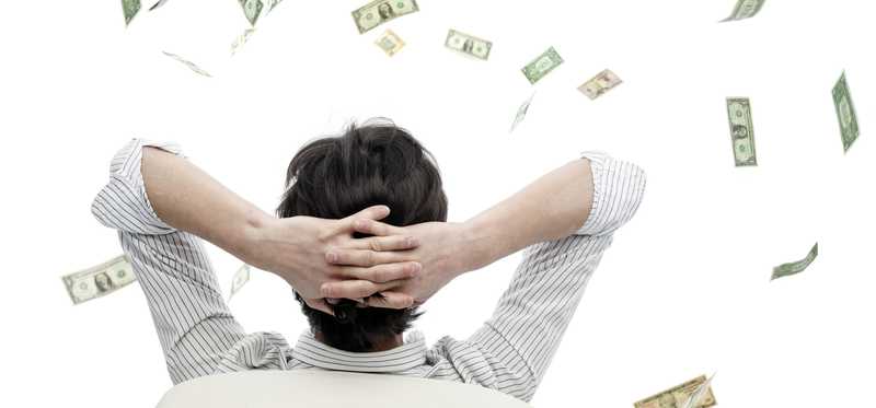 Person leaning back in chair with hands behind their head and watching cash fly through the air.