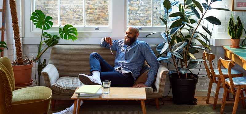 Person smiling while sitting on couch in sun-filled living room.