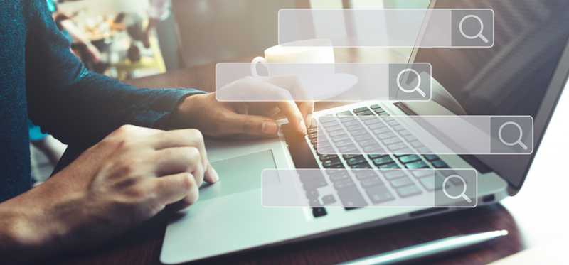 Search engine boxes superimposed over background image of a person typing on laptop.