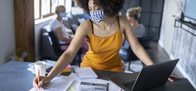 Person wearing face mask in office while reviewing paperwork.