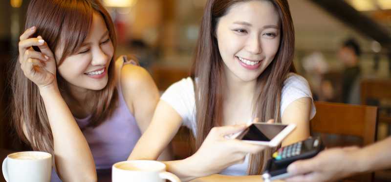 A girl using her phone to make a payment at a coffee shop.