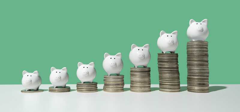 Piggy banks on top of rising stacks of coins.