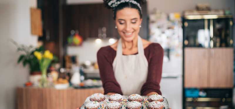 Smiling young woman holding freshly baked cupcakes