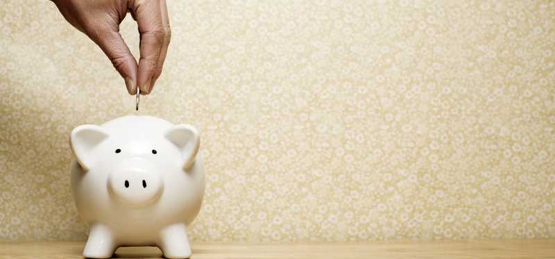 Person putting coin into a piggy bank