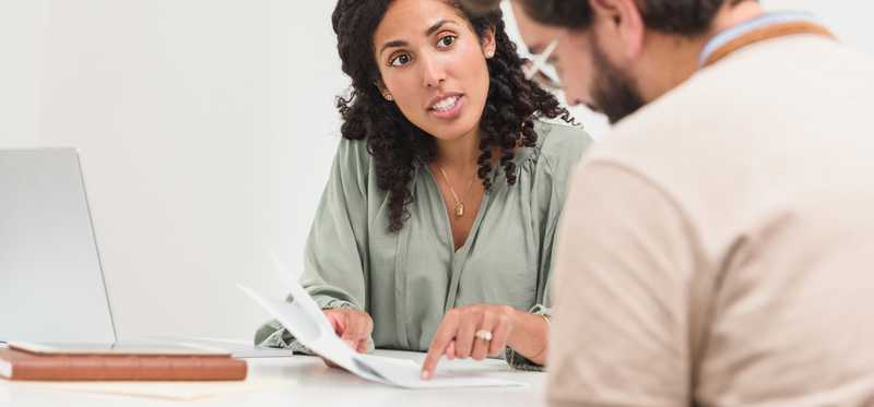 Businessman and businesswoman sitting at table reviewing documents