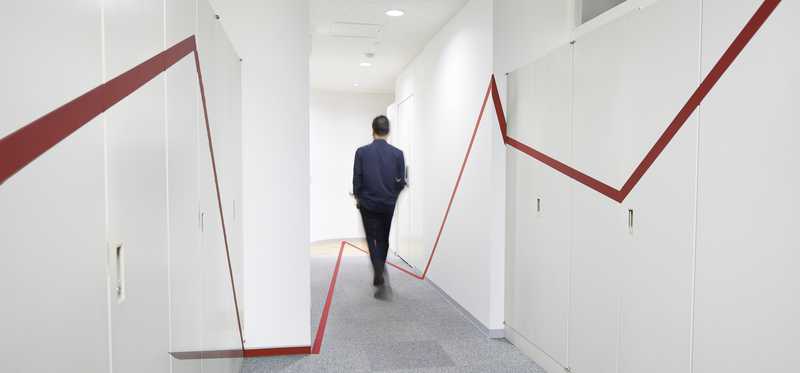 Businessman walking down hallway with red lines going up and down on the walls