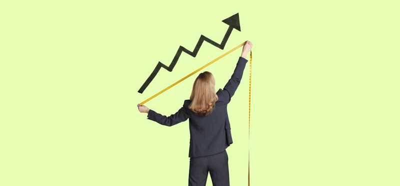 Businessperson is using yellow measuring tape to measure growth of black upward arrow against green background.