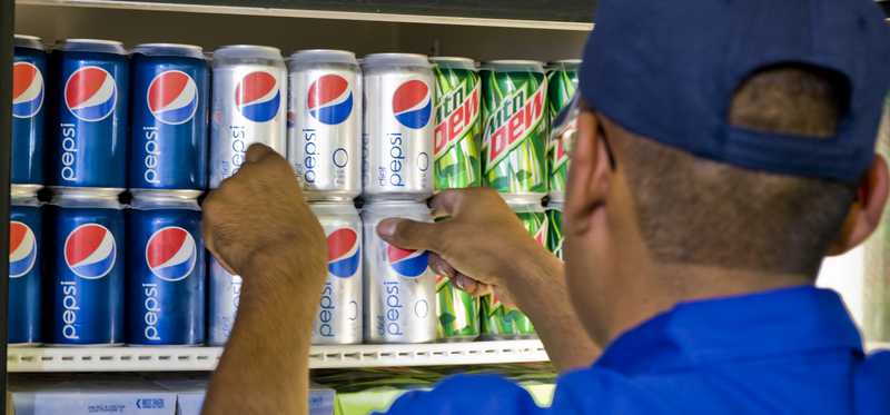 A worker fills a refrigerator with Pepsi products.