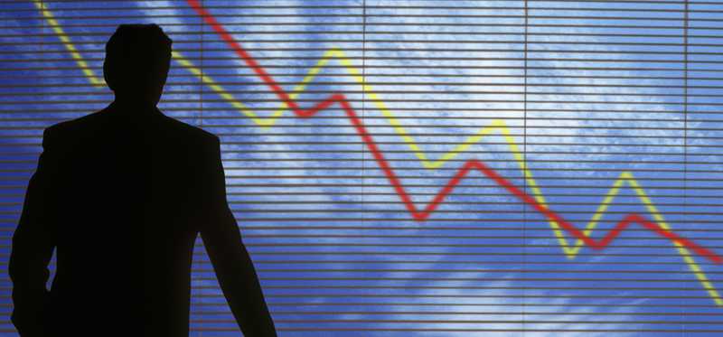 Investor in a dark room watching as markets plummet.